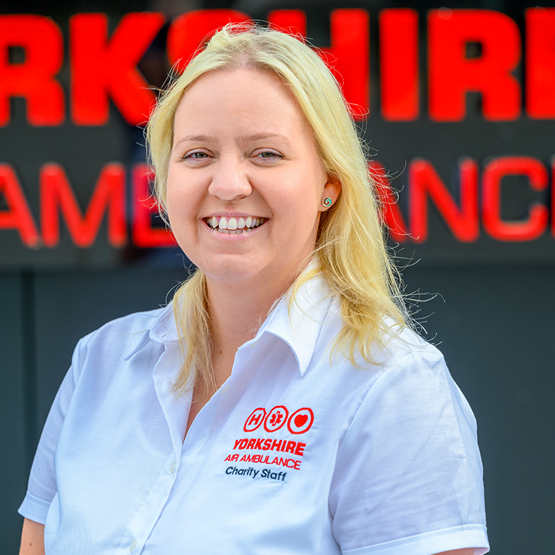 Photo of YAA Digital Marketing Manager Angela Brearley in front of the YAA Logo
