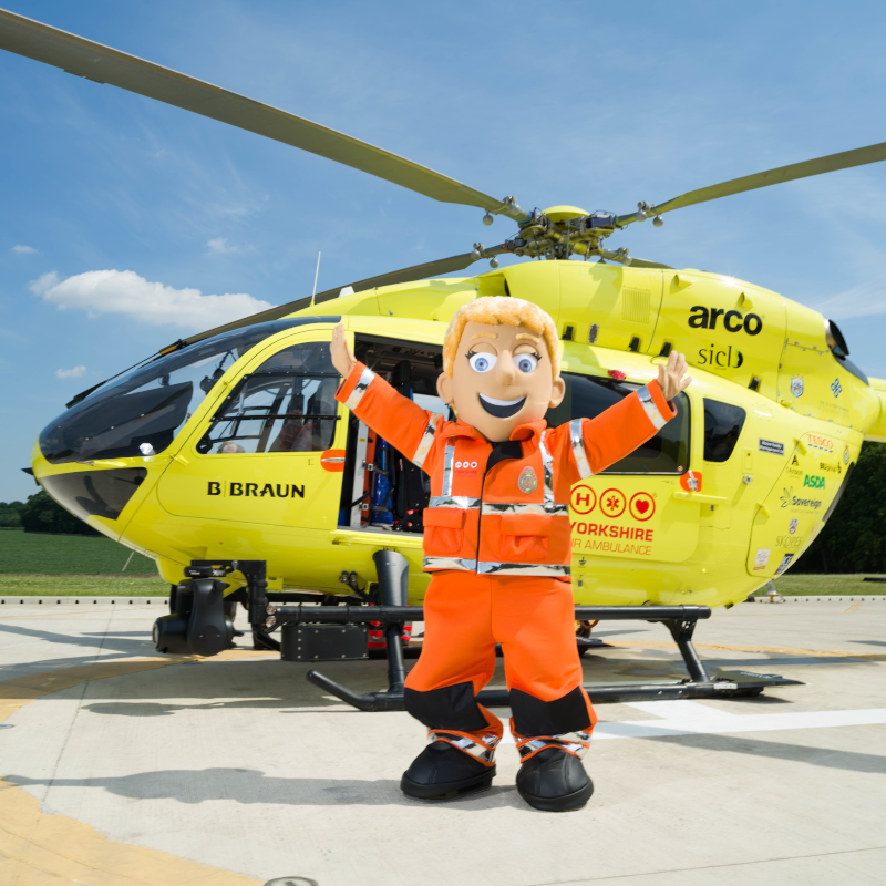 Image of Yorkshire Air Ambulance mascot Polly Paramedic in from of helicopter