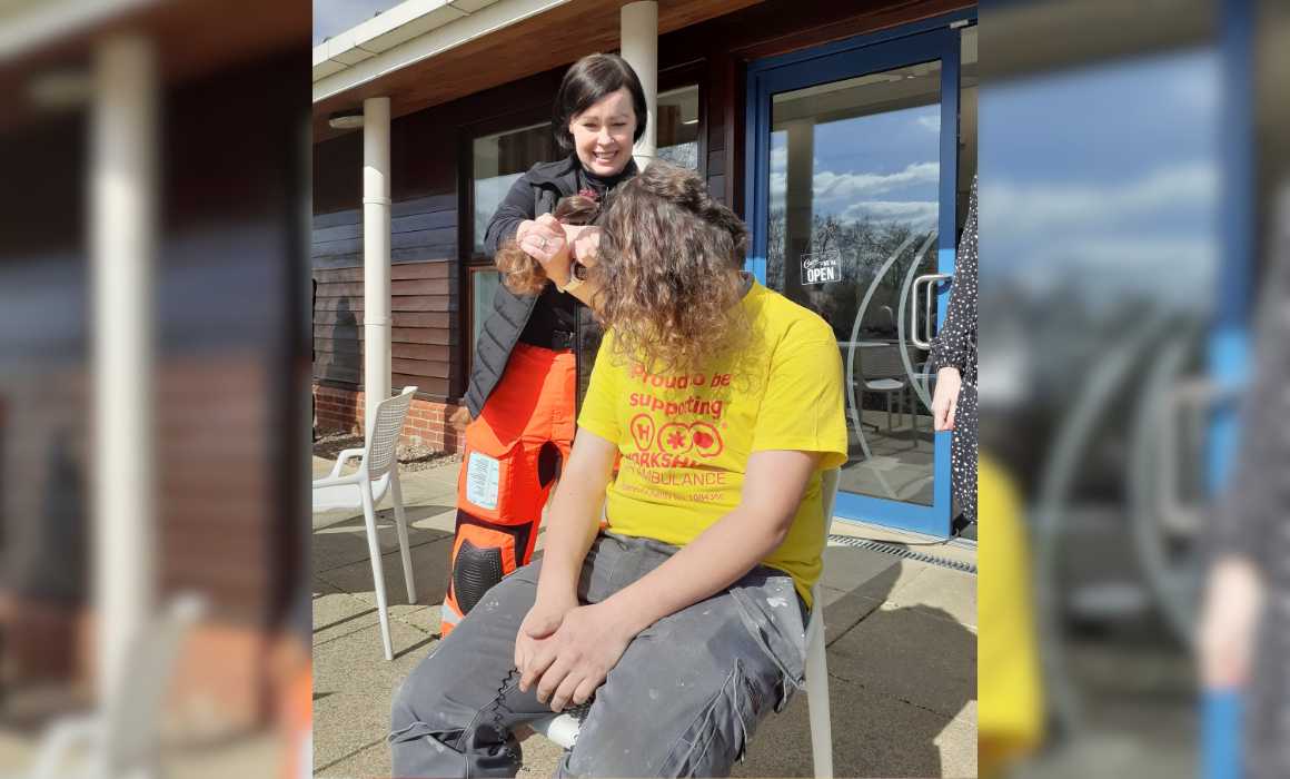 A lady shaving a mans head