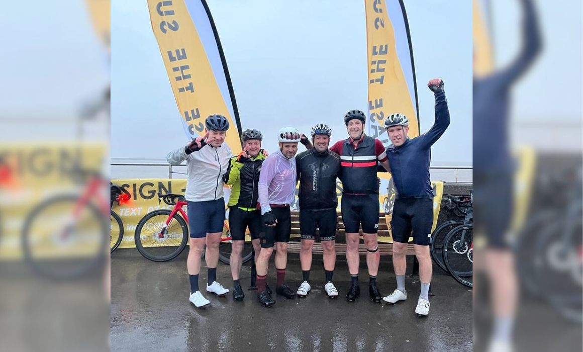 Group of cyclists stood in front of their bikes and flag banners