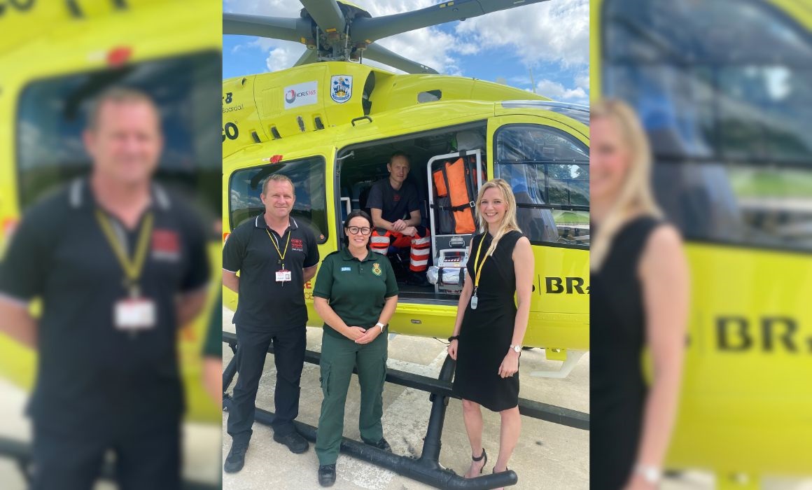 four people in front of a Helicopter