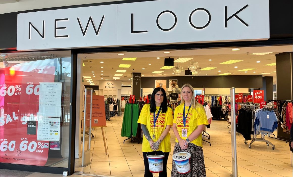 two women outside a high street shop holding collection buckets