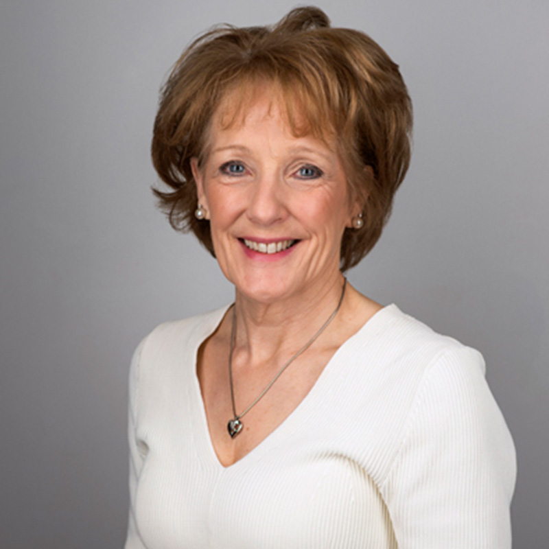 A lady with light brown hair wearing a light cream colour top.